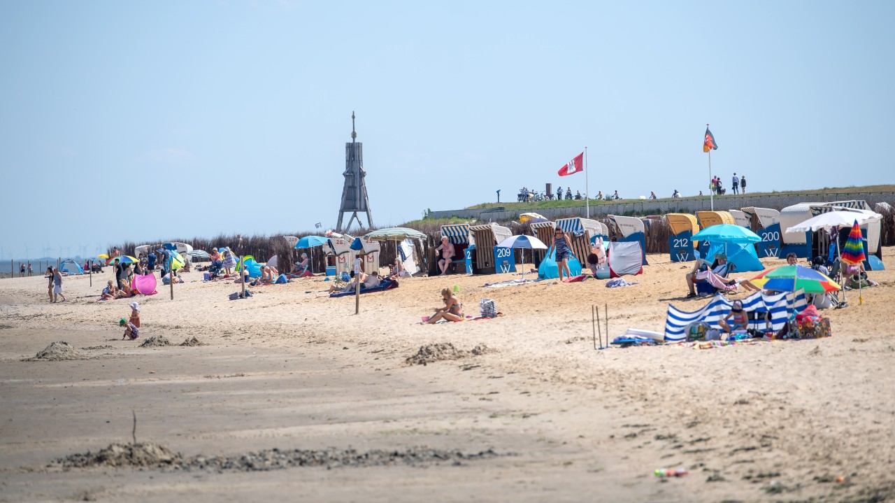 Urlauber sitzen bei Sonnenschein am Nordsee-Strand.