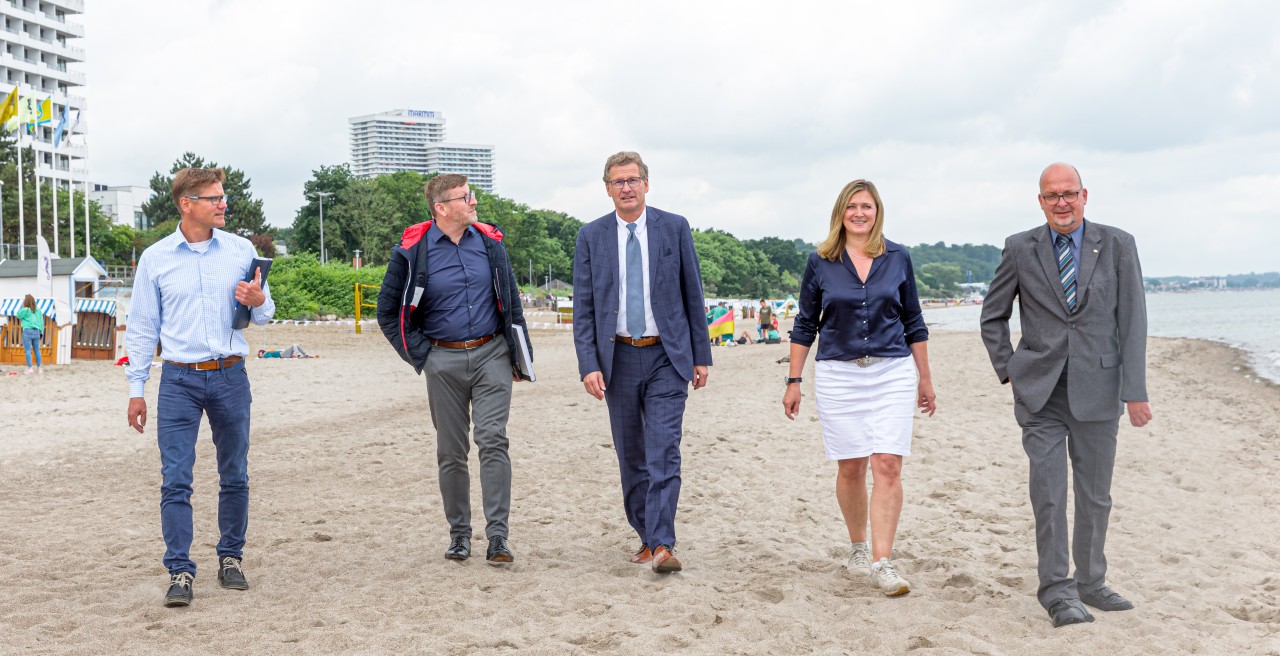 Joachim Nitz (l-r), Tourismusdirektor von Timmendorfer Strand, Sven Partheil-Böhnke (FDP), designierter Bürgermeister von Timmendorfer-Strand, Bernd Buchholz (FDP), Tourismusminister Schleswig-Holsteins, Katja Lauritzen, Geschäftsführerin des Ostsee-Holstein-Tourismus e. V. (OHT), und Jörg Weber, Vorsitzender des Ostsee-Holstein-Tourismus e.V. (OHT) gehen am Ostseestrand entlang.