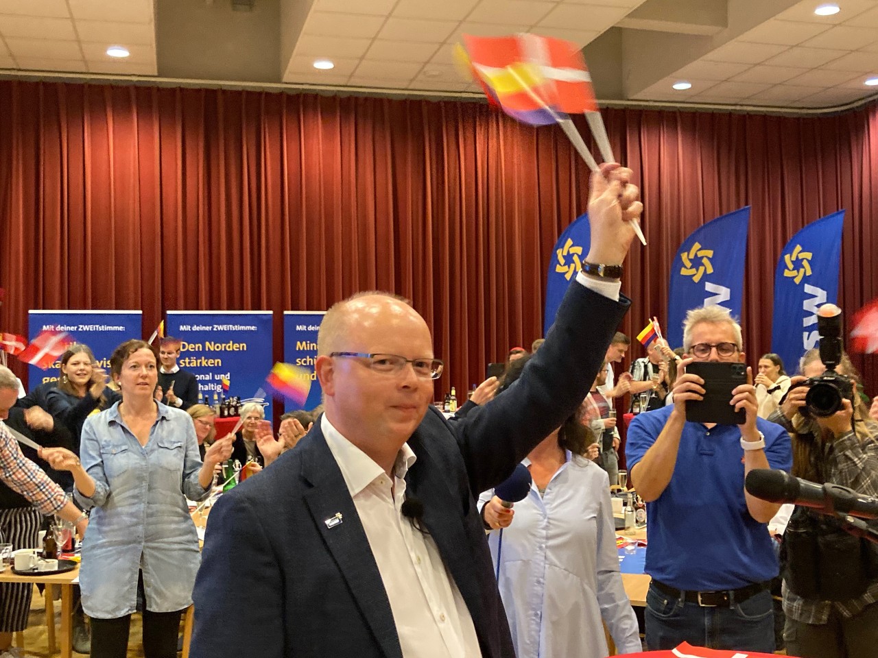 Stefan Seidler, Spitzenkandidat des Südschleswigschen Wählerverbandes (SSW) schwenkt auf der Wahlparty der Partei der dänischen Minderheit und der nationalen Friesen Fähnchen mit dem Dannebrog und den friesischen Farben. Die Partei ist bei der Bundestagswahl von der Fünf-Prozent-Hürde befreit.